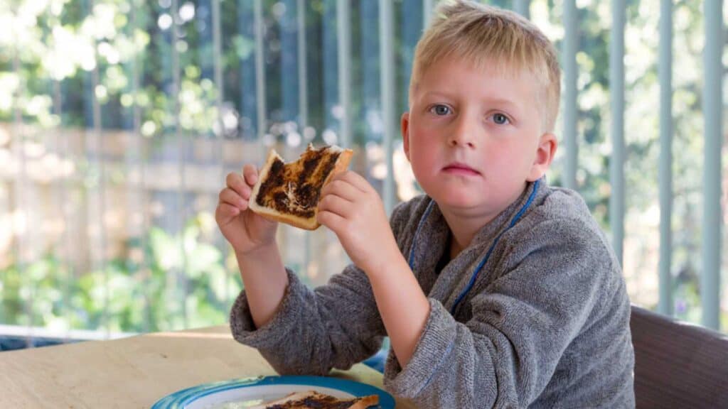 Young boy eating vegemite toast for breakfast