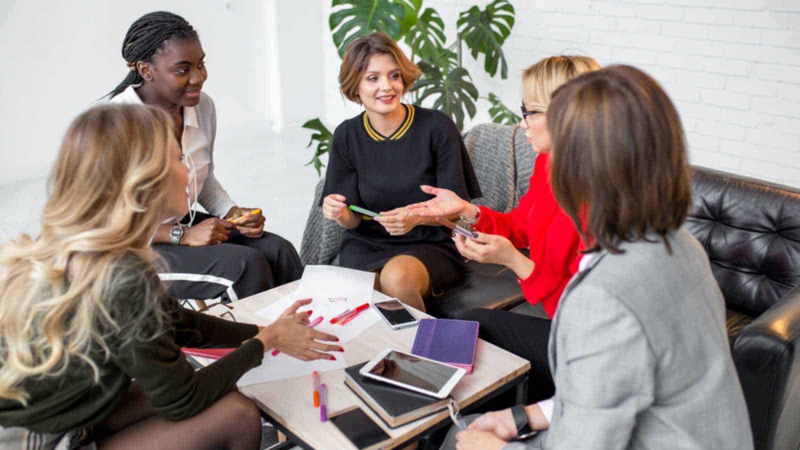 Female co-workers discussing together commercial project collaborating with team leaders supervising staff job. Multi- ethnic MLM team at working process.