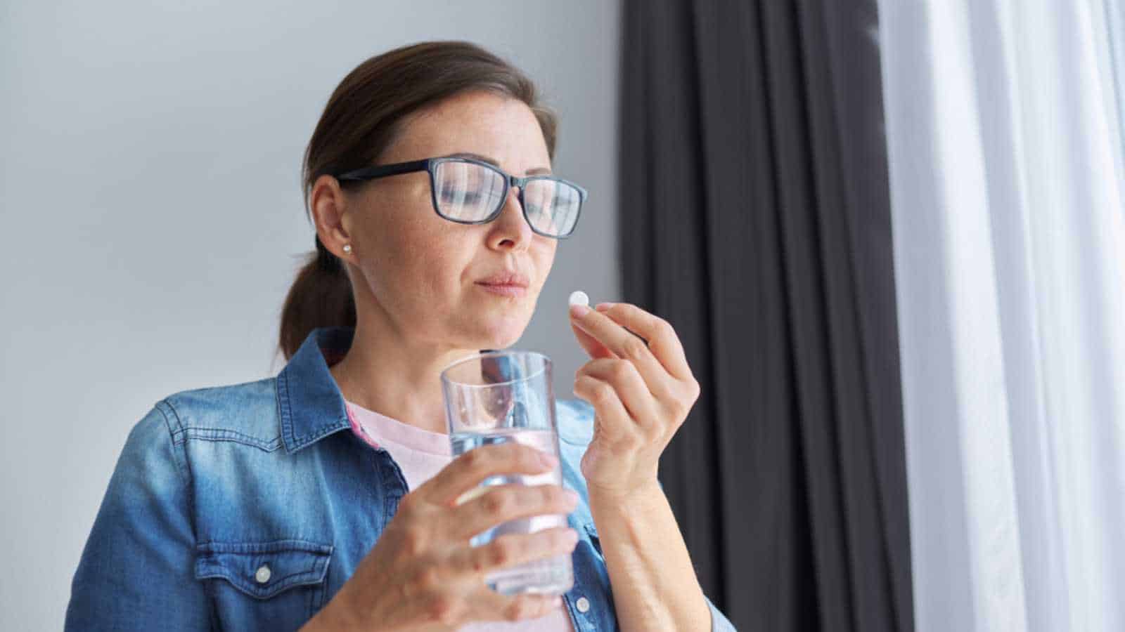 Woman with water taking medicine