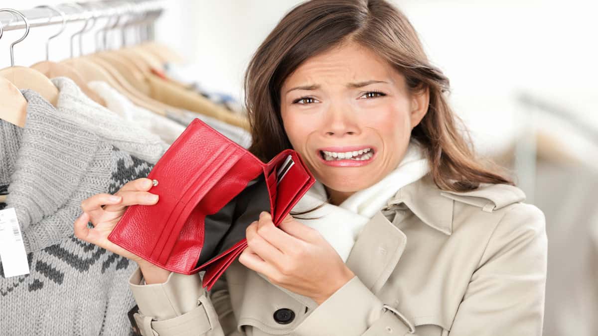sad woman holding wallet with no money