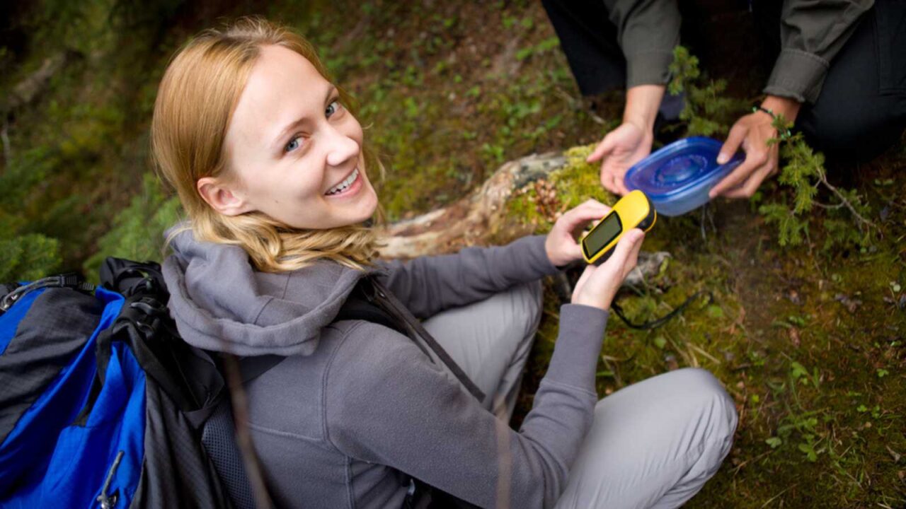 A young woman finding a geocache in the forest