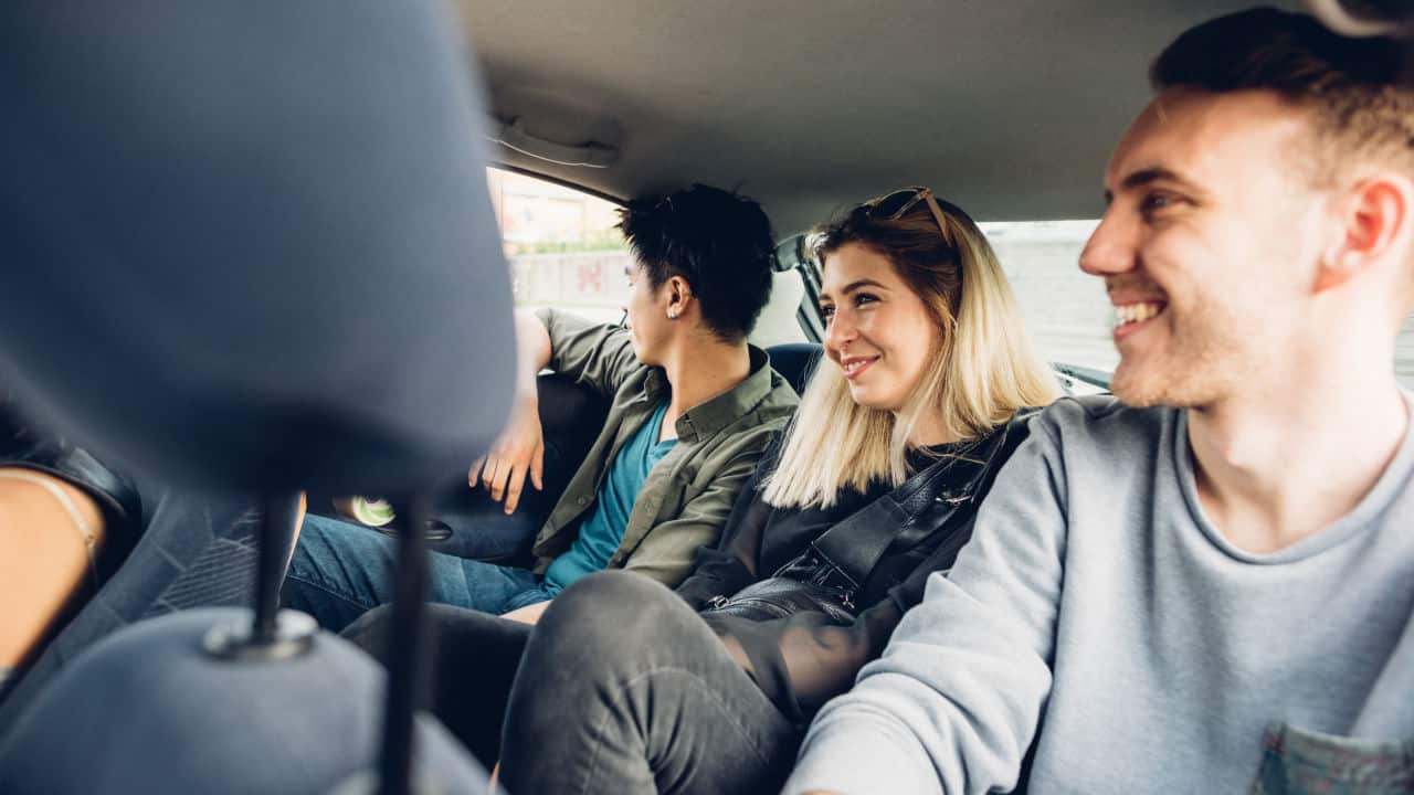Group of friends multiethnic millennials view from automobile window traveling by car