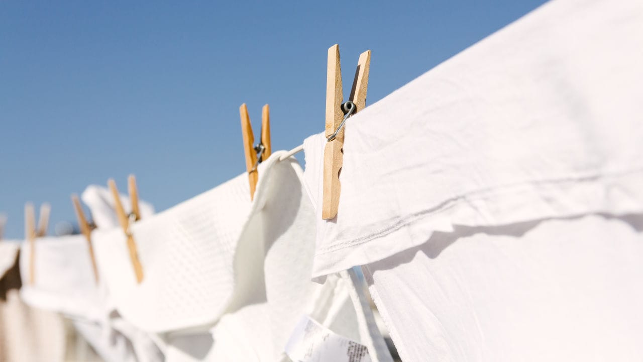 White clothes hung out to dry on a washing line in the bright warm sun.