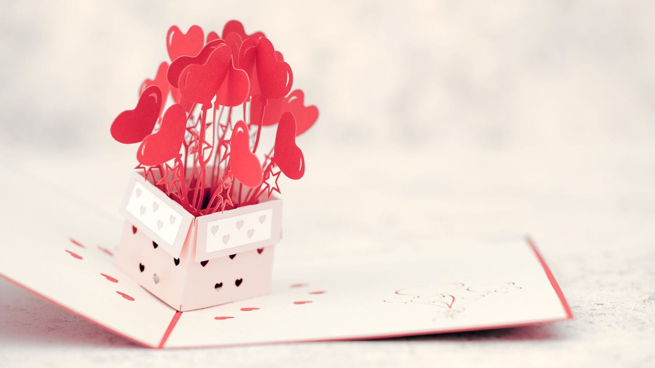 A red pop up card with heart shapes bursting out