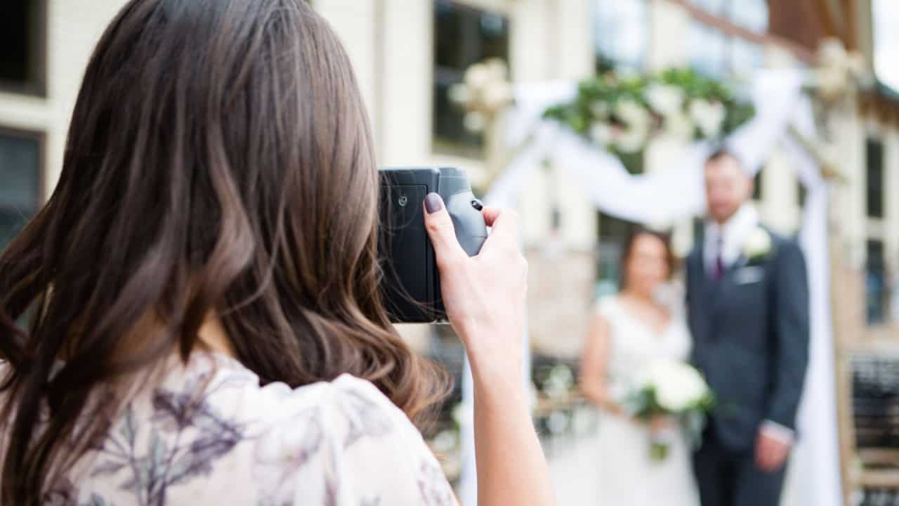 Woman taking photo of bride and groom