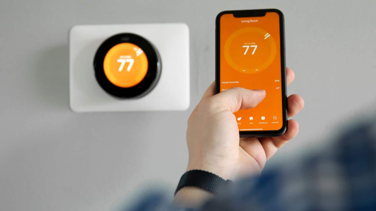 Man uses a mobile phone with smart home app in modern living room