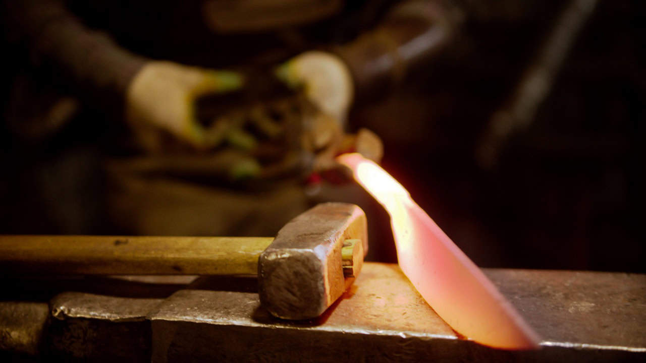 A man blacksmith making a knife out of metal