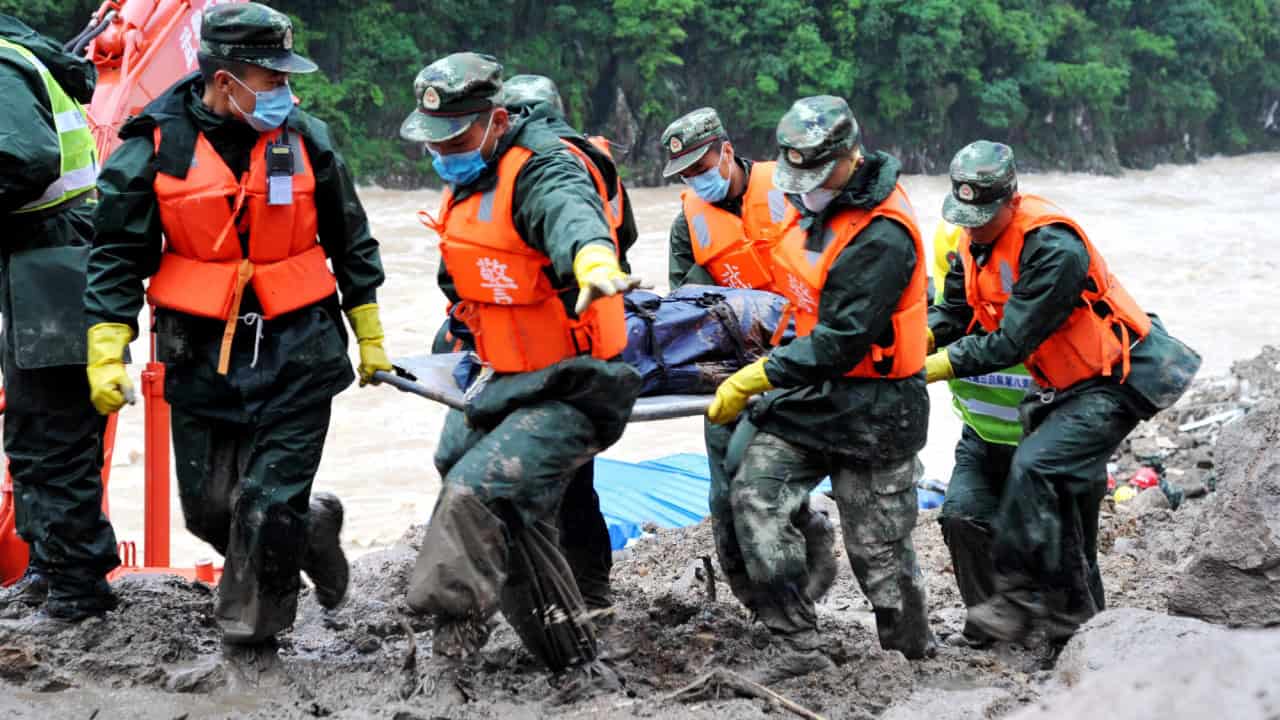 Chinese rescuers carry the body of a victim found in disaster