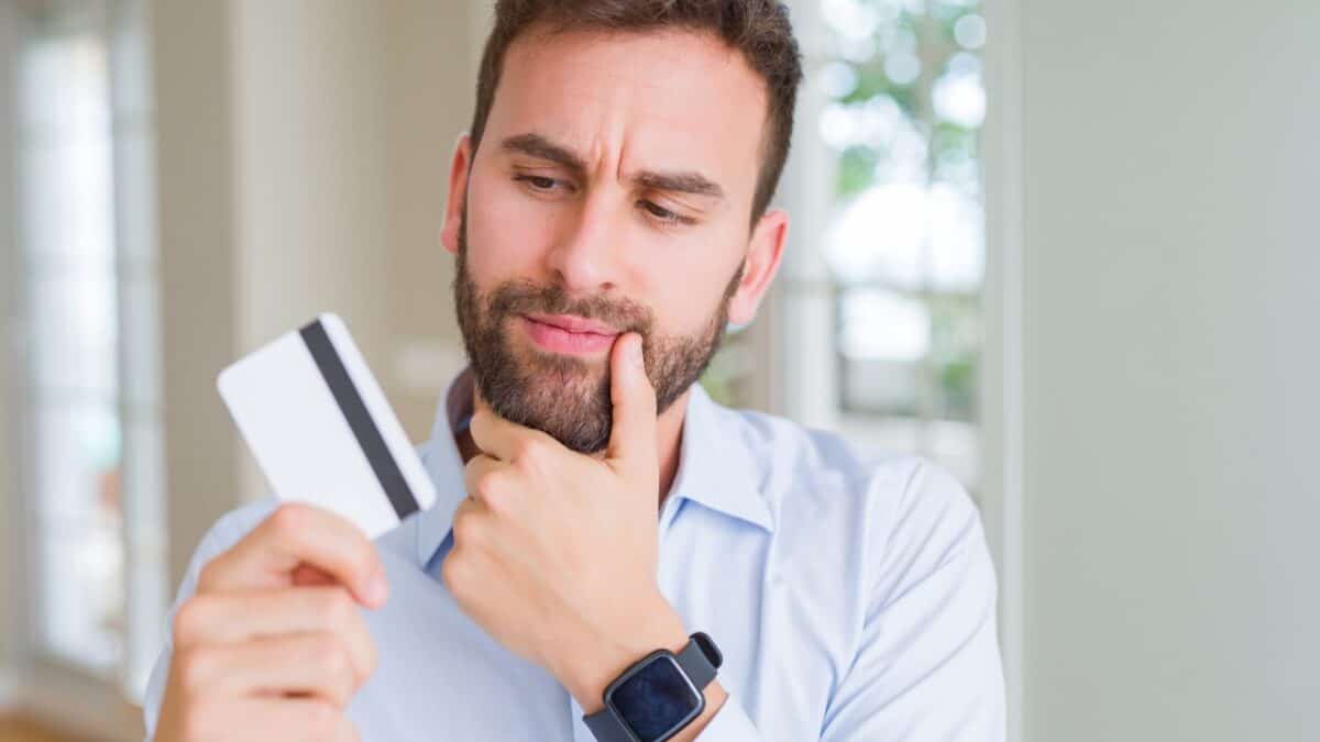 man holding credit card serious face thinking