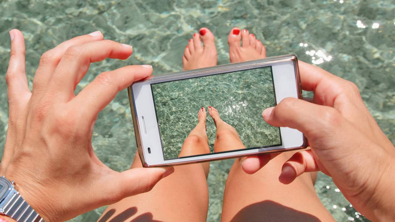 Woman taking photos of his feets on the sea