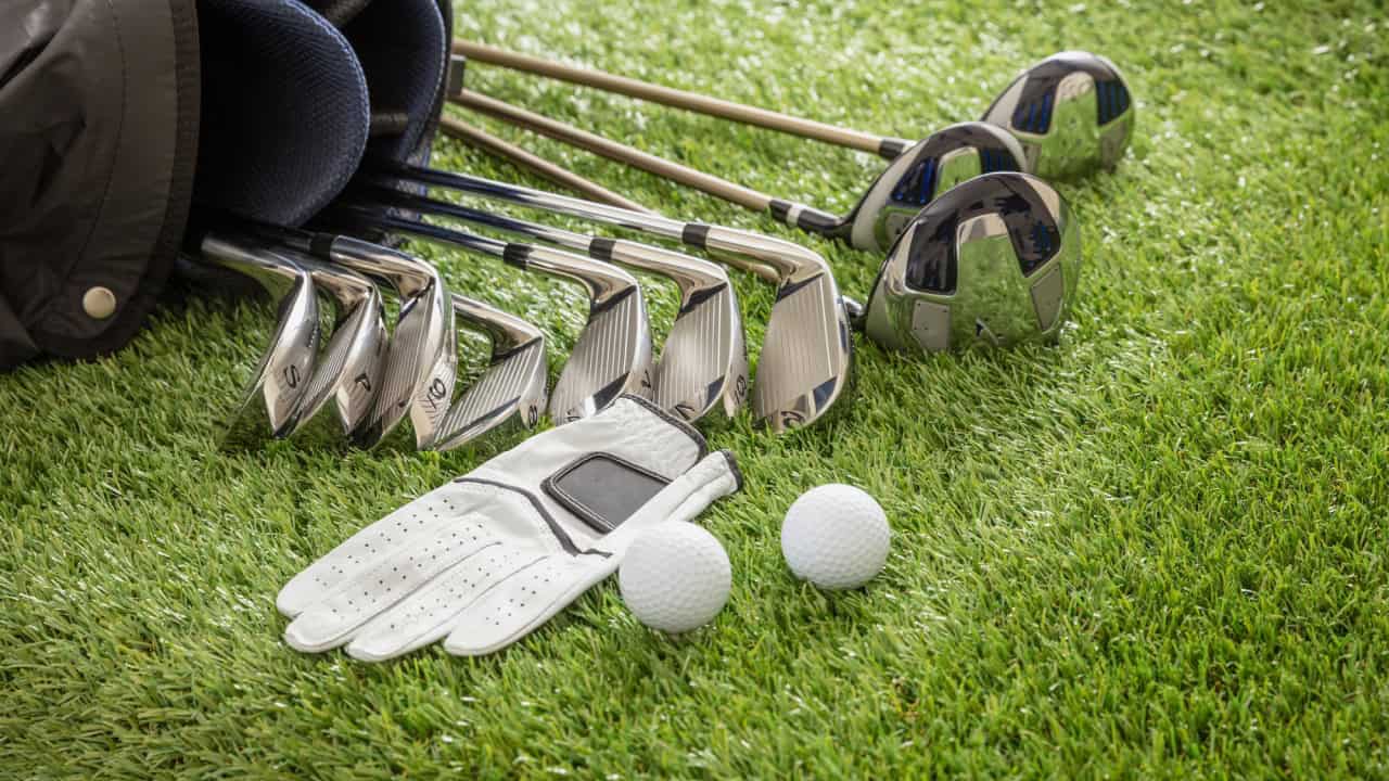 Golf equipment, sticks set in a bag glove and golfballs on green course