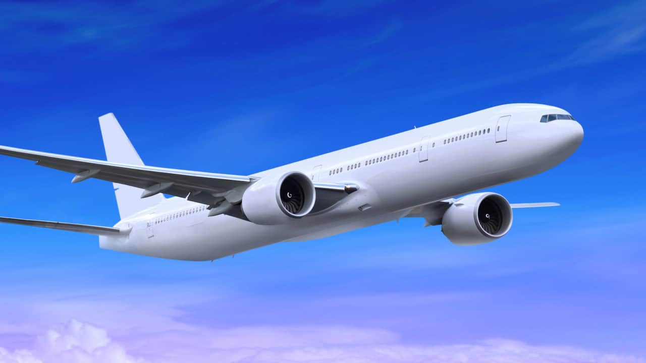 White passenger plane is landing away in the blue sky