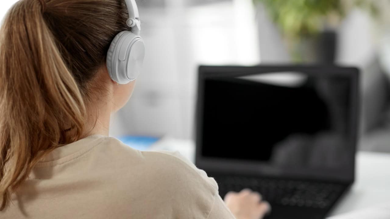 woman in headphones with laptop at home transcribing