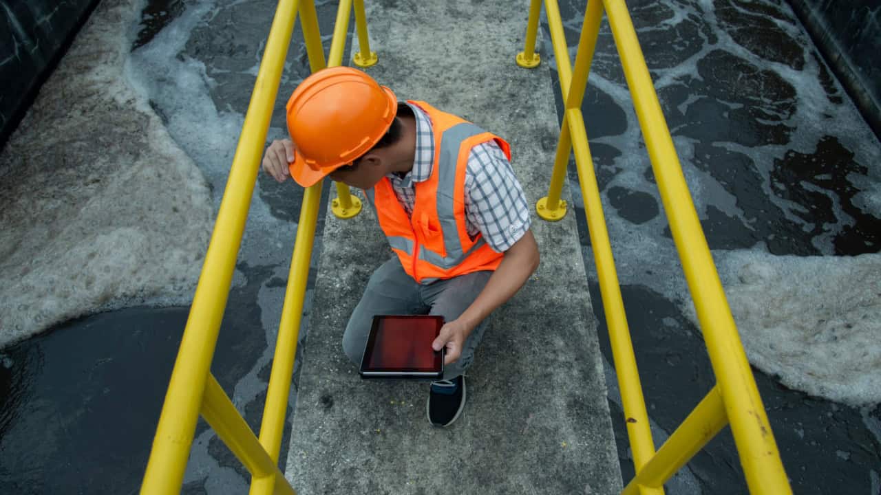 service engineer checking on waste water treatment plant with pump on background